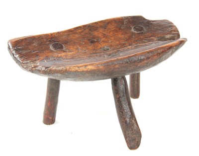 Lot 1036 - AN EARLY PRIMITIVE WALNUT MILKING STOOL with...