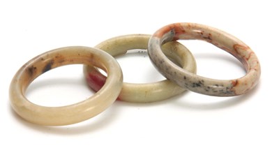 Lot 197 - THREE CHINESE RUST JADE BANGLES 92mm, 93mm and...