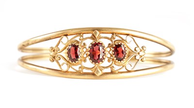 Lot 353 - A LADIES 9CT GOLD AND GARNET SET BANGLE of...