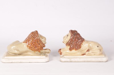 Lot 28 - A PAIR OF 19TH CENTURY GLAZED PAINTED STONEWARE RECUMBENT LIONS