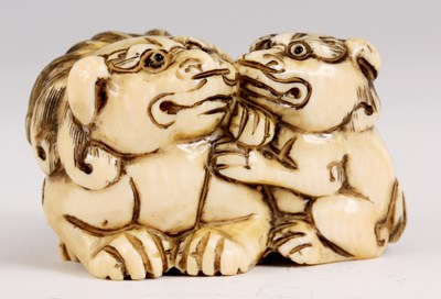 Lot 89 - AN IVORY NETSUKE IN THE FORM A FOO DOG WITH...