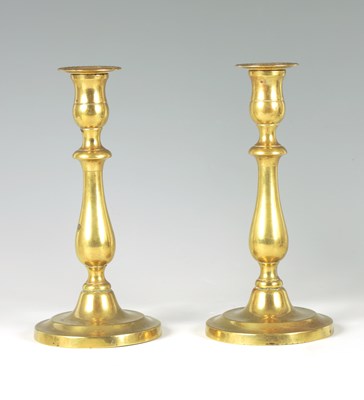 Lot 608 - A PAIR OF 18TH CENTURY CIRCULAR BASE BRASS CANDLESTICKS