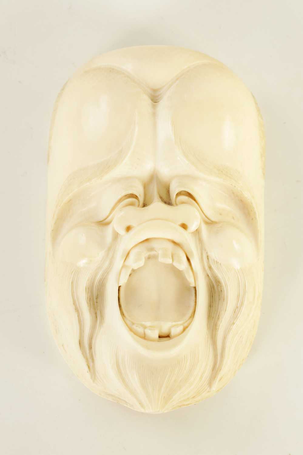 Lot 120 - A JAPANESE MEIJI PERIOD CARVED IVORY GROTESQUE FACE MARK
