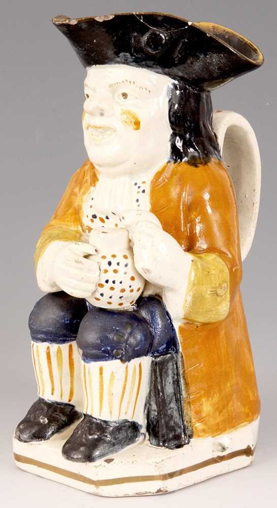 Lot 30 - A GEORGE III STAFFORDSHIRE TOBY JUG the seated...