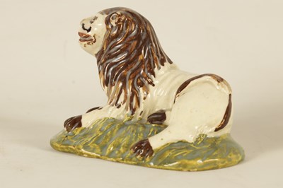 Lot 32 - AN EARLY 19TH CENTURY STAFFORDSHIRE SCULPTURE OF A RECUMBENT LION