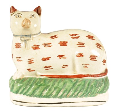 Lot 67 - AN EARLY 19TH CENTURY STAFFORDSHIRE MODEL ON A RECUMBENT CAT