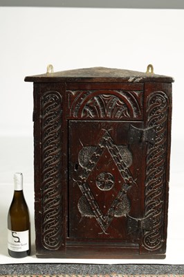 Lot 1025 - A 17TH-CENTURY SMALL CARVED OAK HANGING CORNER CUPBOARD