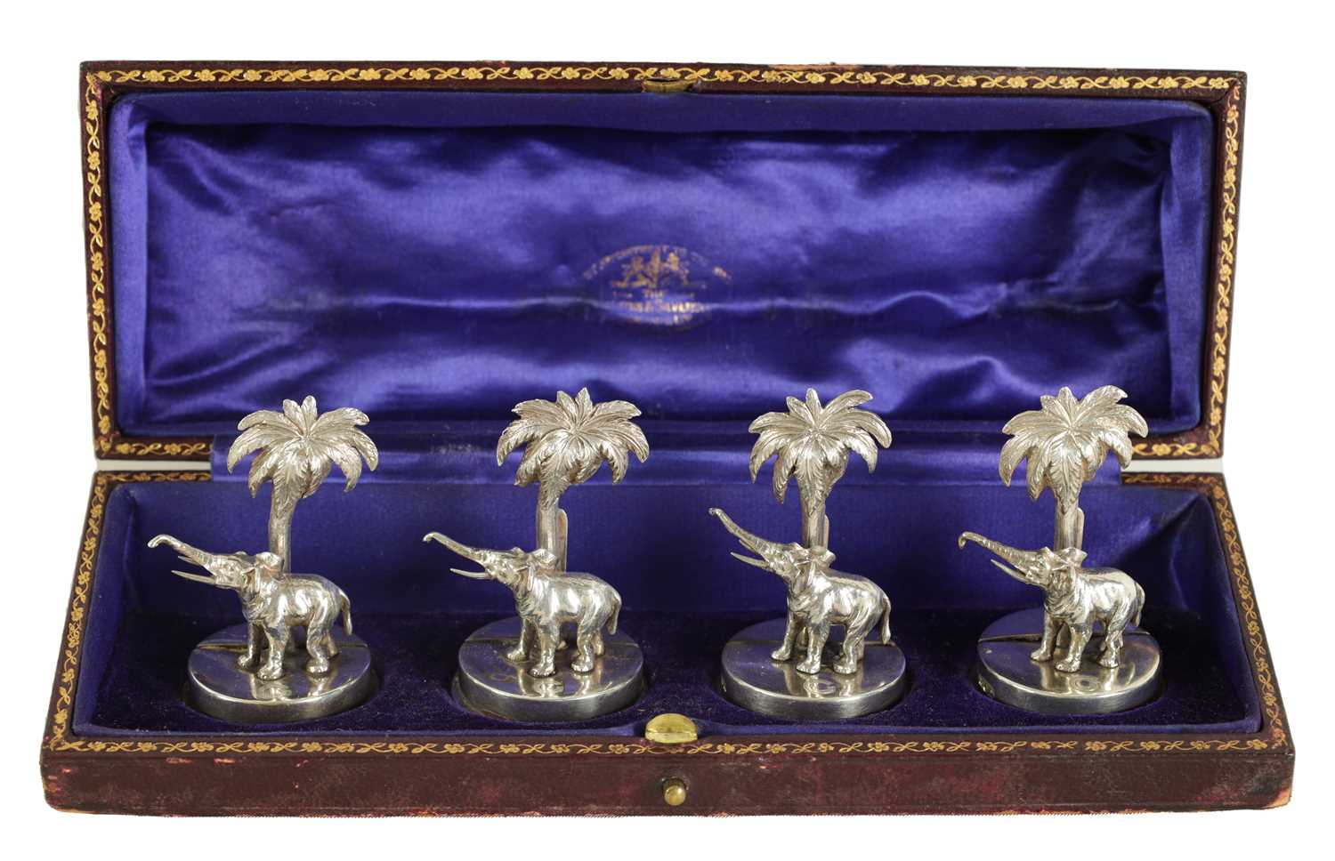 Lot 327 - A CASED SET OF FOUR SILVER ELEPHANT AND PALM TREE MENU HOLDERS