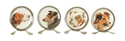 Lot 433 - A CASED SET OF FOUR CIRCULAR SILVER AND PAINTED DOG'S HEAD MENU HOLDERS