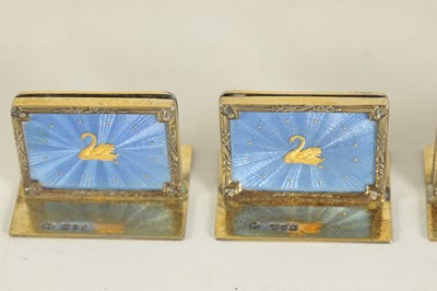 Lot 479 - A CASED SET OF FOUR SILVER GILT AND BLUE GUILLOCHE ENAMEL MENU HOLDERS