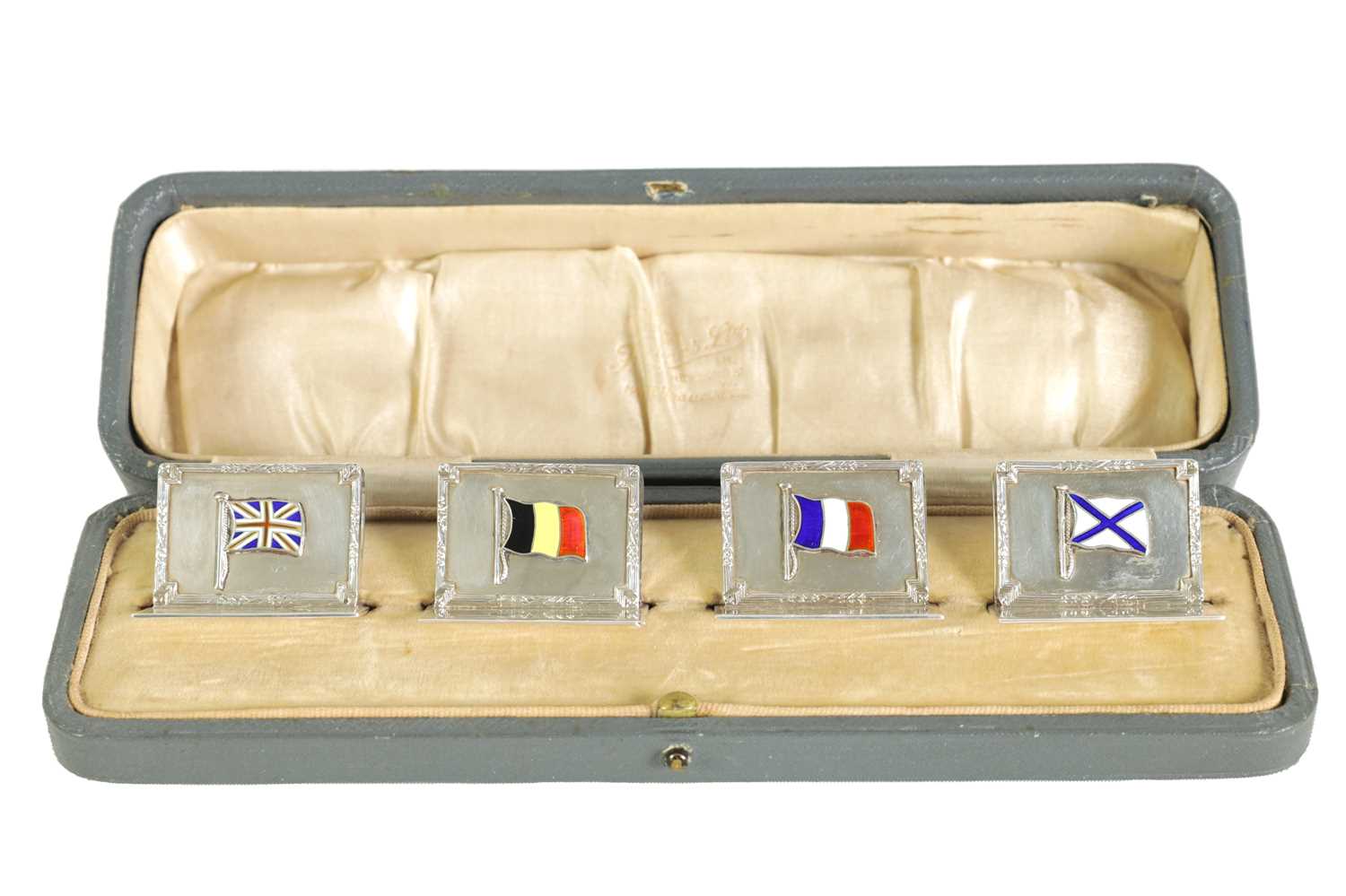 Lot 340 - A CASED SET OF FOUR SILVER AND ENAMEL FLAG MENU HOLDERS