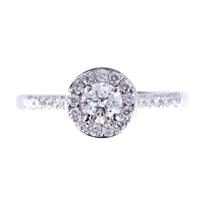 Lot 19 - A PLATINUM SOLITAIRE DIAMOND RING with halo...