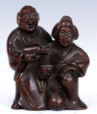 Lot 100 - A JAPANESE HARDWOOD NETSUKE of a man pouring...