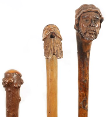 Lot 484 - TWO MASK HEAD CARVED WOOD WALKING STICKS AND A RIDING CROP