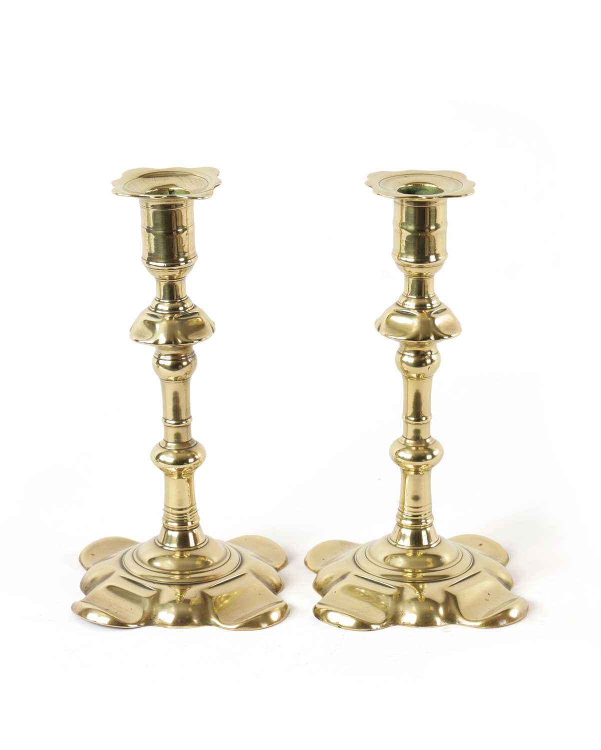 Lot 658 - A PAIR OF EARLY 18TH CENTURY SEAMED BRASS PETAL BASE CANDLESTICKS