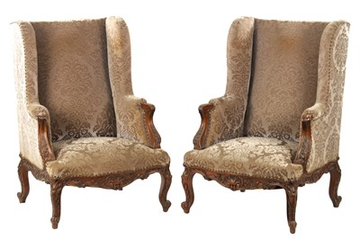 Lot 834 - A PAIR OF 18TH CENTURY FRENCH OVERSIZED CARVED WALNUT UPHOLSTERED WINGBACK ARMCHAIRS