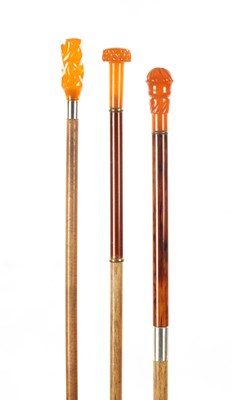 Lot 744 - A COLLECTION OF THREE LATE 19TH CENTURY AMBER TYPE TOPPED WALKING STICKS