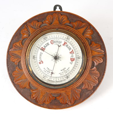 Lot 624 - AN OAK CASE ANEROID BAROMETER with carved leaf...