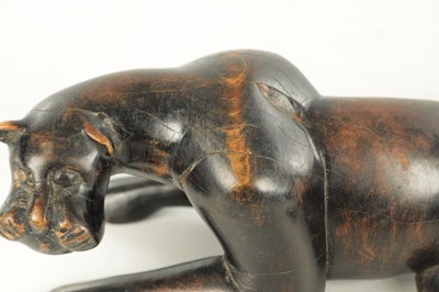 Lot 894 - A 19TH/EARLY 20TH CENTURY CARVED STAINED HARDWOOD SCULPTURE OF A RECUMBENT BIG CAT