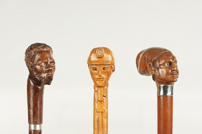 Lot 496 - A COLLECTION OF THREE LATE 19TH CENTURY CARVED WOOD MASK HEAD WALKING STICKS