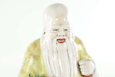 Lot 659 - AN EARLY 20TH CENTURY CHINESE PORCELAIN FIGURE OF AN ELDER HOLDING FRUIT